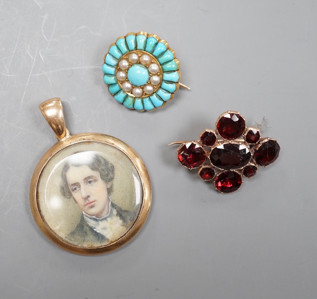 A Victorian yellow metal, turquoise and split pearl set circular brooch, 19mm, a similar garnet set brooch and a 15ct mounted miniature portrait pendant.